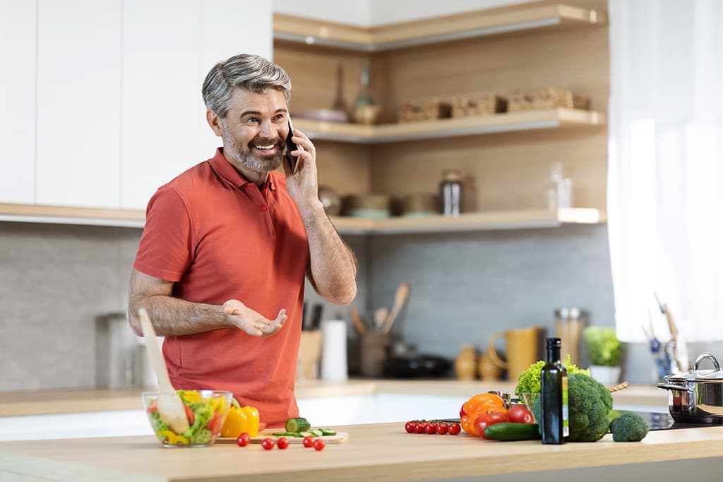 Mature man in kitchen talking on phone.