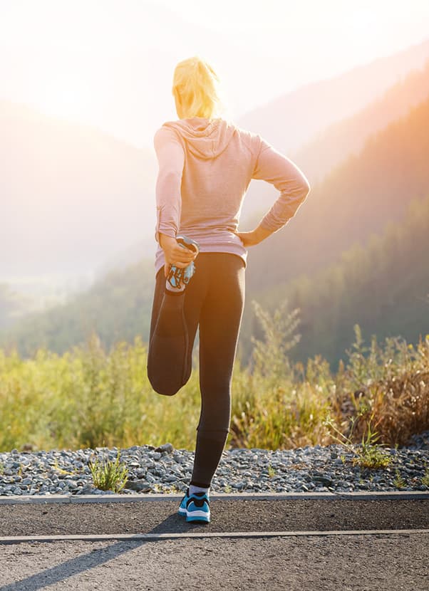 A woman stretching with a mountainous backdrop.